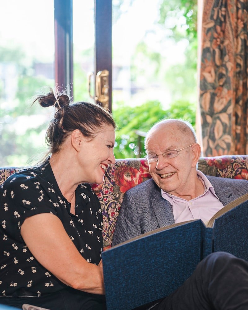 A caregiver and a senior sharing a book on the couch in a sunlit Ottawa home